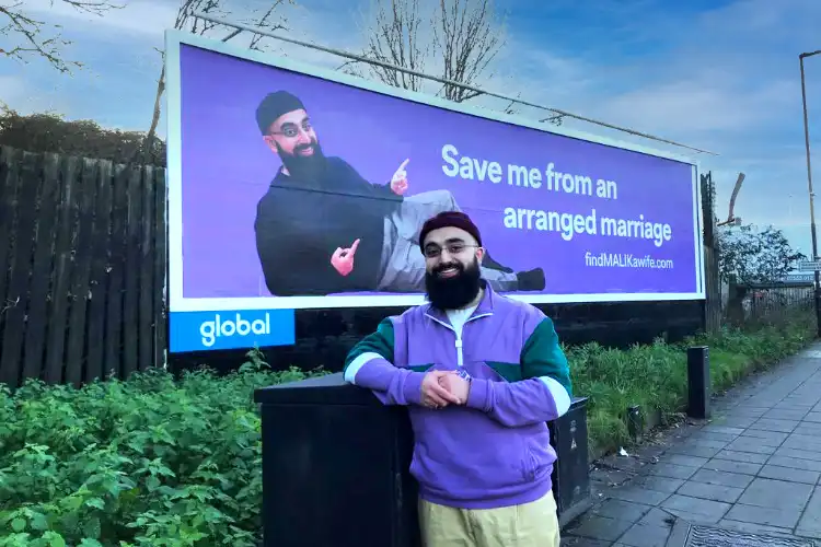 Muhammad Malik standing in front of his Bill Board in Birmingham, UK