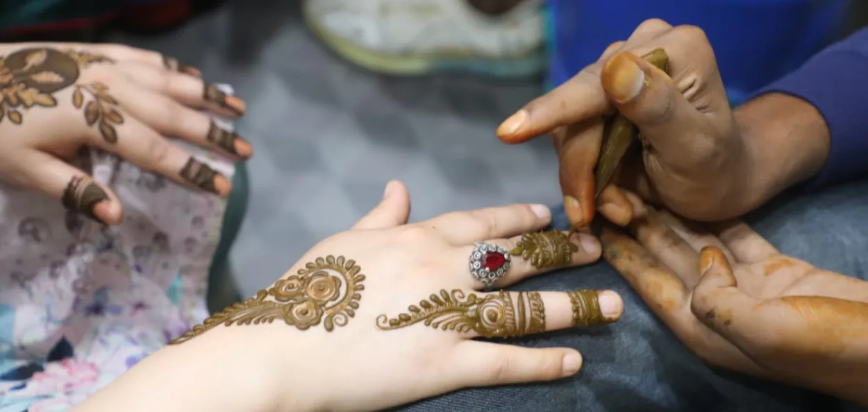 Women getting henna tattoos on hand 