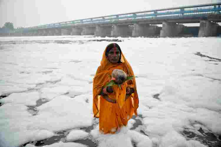 A woman offering argh to Sun God on Chhath in Yamuna