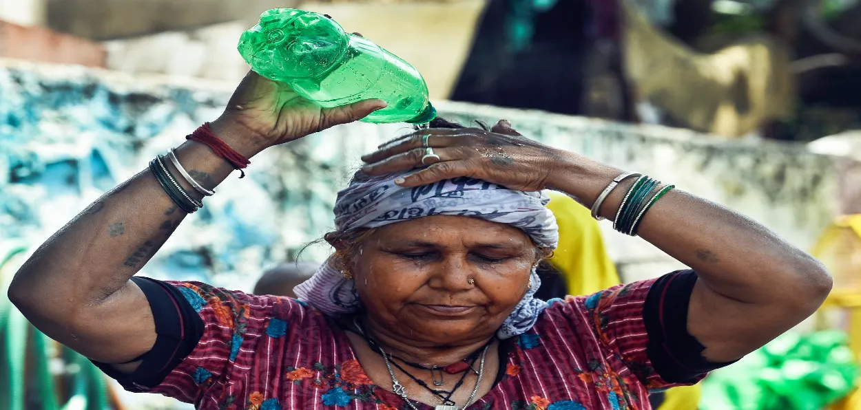 A women pours water over her head to beat the heat