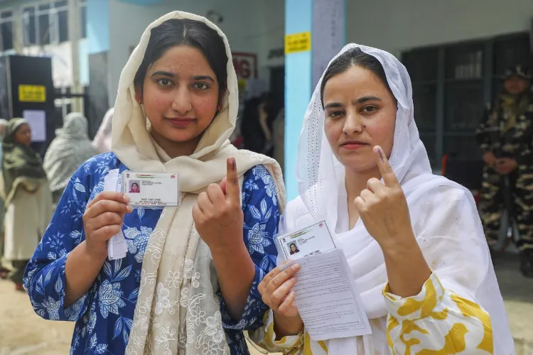 Women voters show inked fingers after voting at a polling station during the first phase of Assembly elections in Kulgam, south of Srinagar