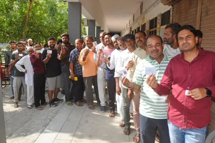 Voters wait in a queue to cast their votes at a polling station in Sonipat