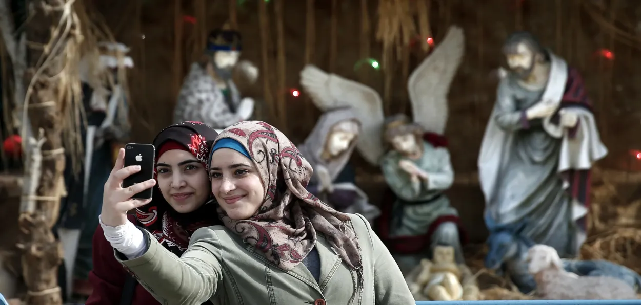 Muslim women taking pictures with statue of Jesus in a Church