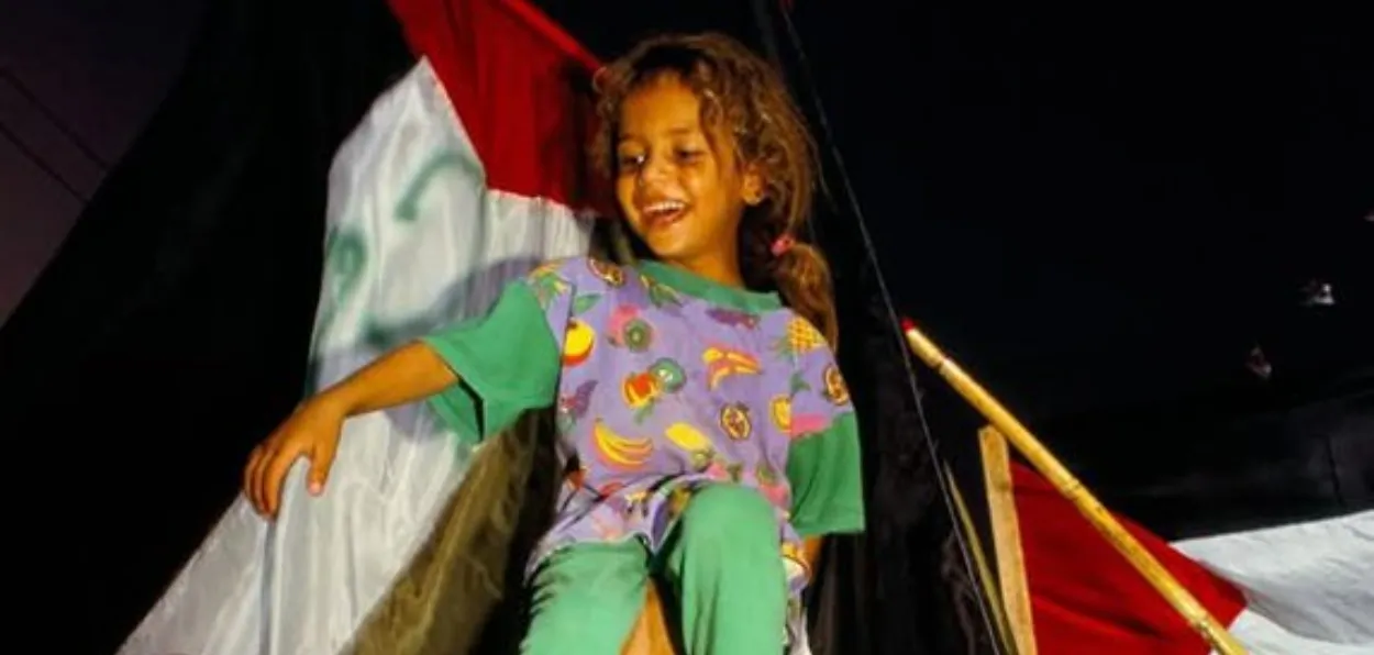 A Palestinian child beaming with joy as elders lift in to celebrate the end of the war in Gaza (X)