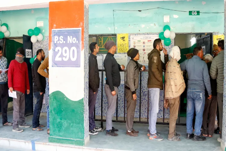 Voters queue up to cast their votes for the Delhi Assembly Elections